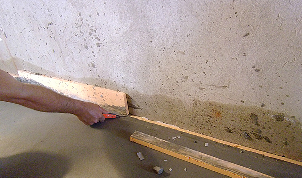 На фото – отрезаем излишки термошва стяжки пола