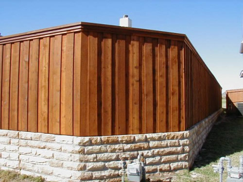 Деревянный забор, поднят от грунта на цоколе. Сверху на заборе крышка. 