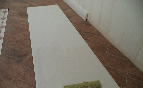 нанесение клея валиком на полосу обоев