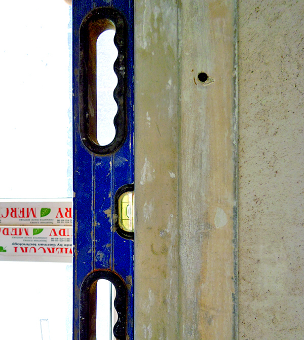 На фото изображен процесс установки уровня ограничителя для доводки боковых плоскостей проема